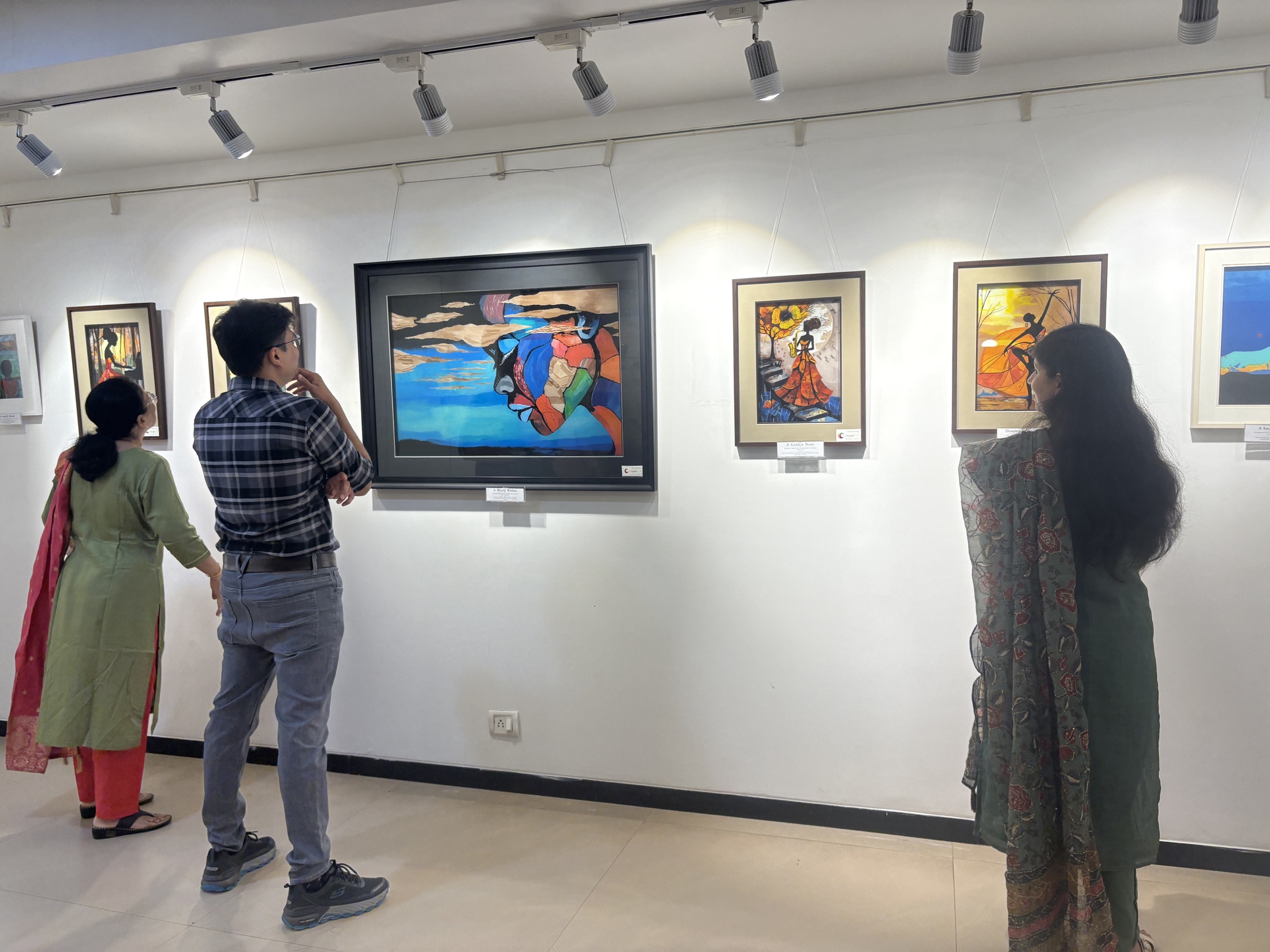 Visitors viewing Nitin Mistry's reverse glass paintings at Unfinished Artistry